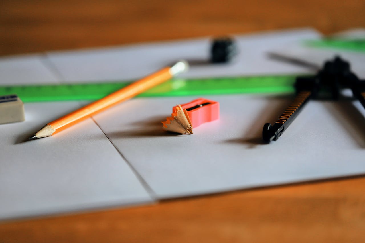 A close-up view of stationery essentials including pencil, sharpener, eraser, ruler, and compass.